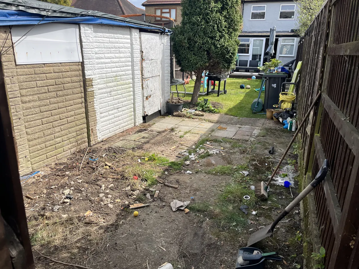 The old garage at the bottom of the garden, with its roof covered in a blue tarp