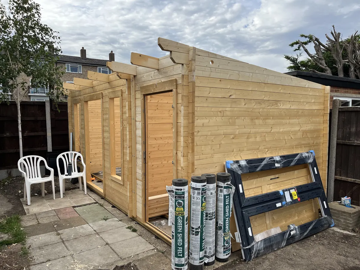 The roof beams across the top of the cabin, with rolls of roofing felt and a uPVC window frame leaning against it