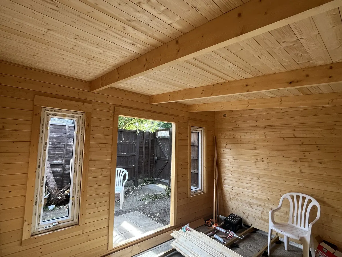 Inside the main room looking at the uPVC windows and door frame, with the roof beams overhead