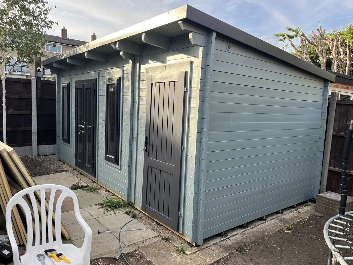 The finished cabin from the side, showing the side store door and the length of the building